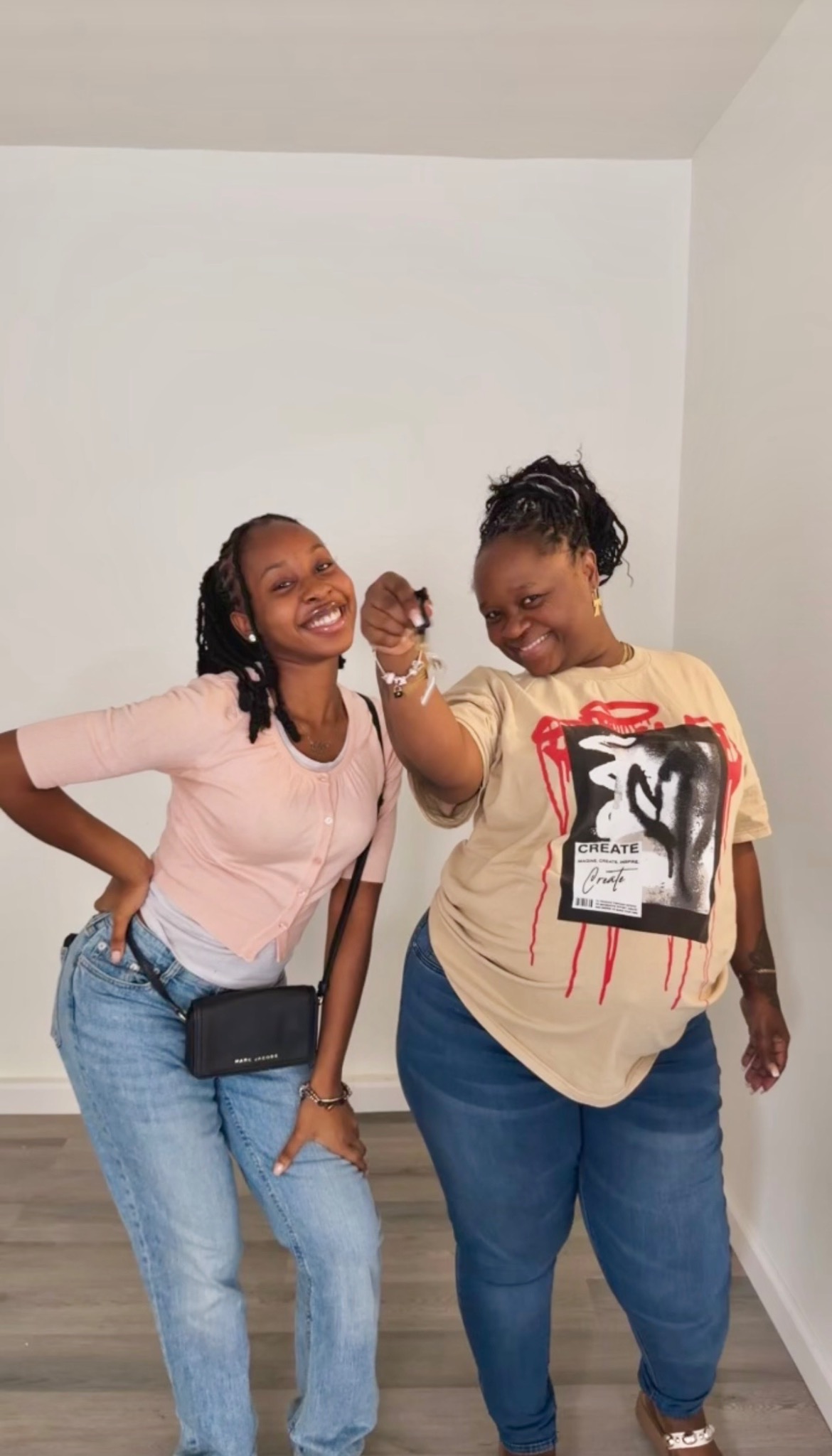 Two people smiling in an empty apartment, with one holding up keys